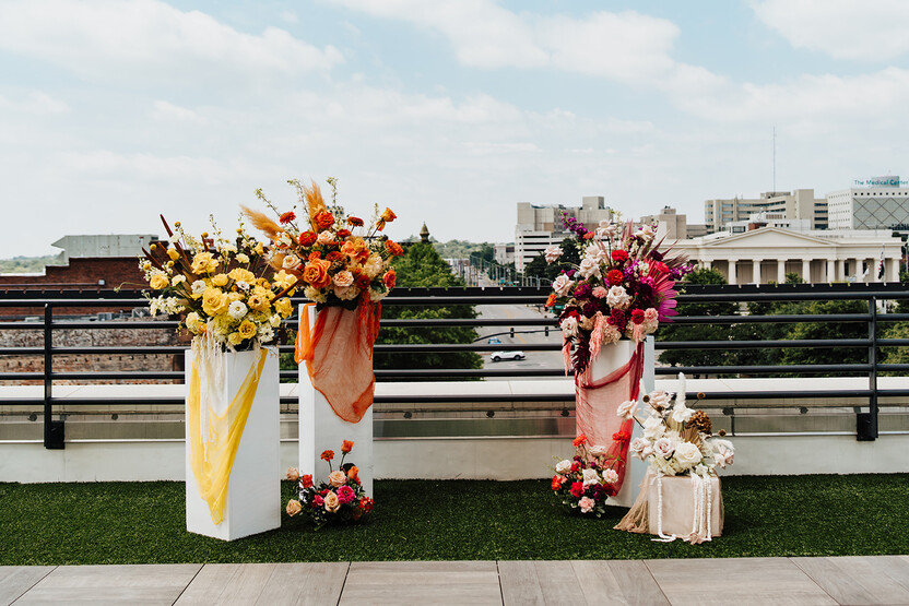 columns on a balcony have pink, orange, and yellow flowers and material. This is the spot for a ceremony at one of the Scottsdale wedding venues.