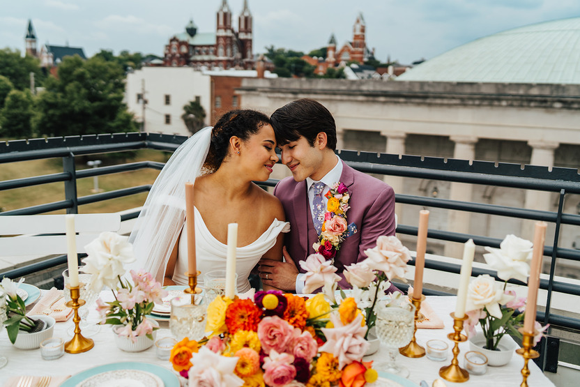 Bride and groom touch foreheads at the sweet hearts table at their wedding reception on a balcony of one of the Scottsdale wedding venues.