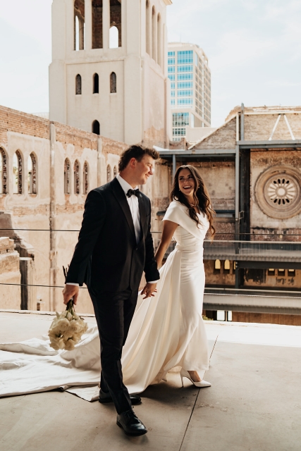 Scottsdale bride and groom stand on a balcony inside The Abbey on Monroe with beautiful industrial architecture behind them.