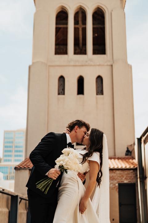 Bride and groom kiss at Scottsdale Wedding venue The Abbey on Monroe in front of the bell tower